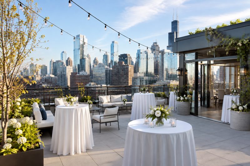 Chicago rooftop arranged for a company networking event with skyline views, cocktail tables, lounge seating, and warm evening lighting