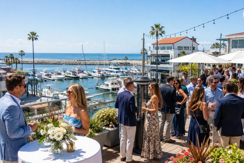 Private event guests on a Redondo Beach harbor terrace with marina views