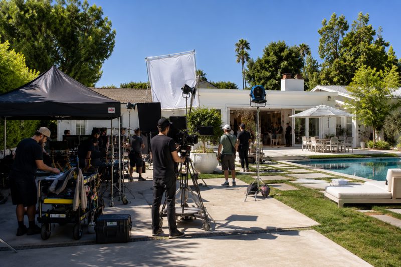 Small production crew setting up camera gear at a San Fernando Valley home with driveway access