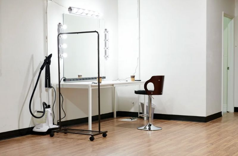 Spacious photo studio with natural light, seamless backdrops, and makeup station